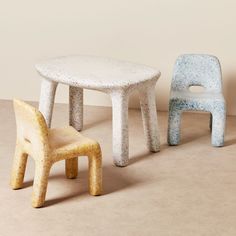 two chairs and a table in the shape of children's chairs, one is made out of concrete