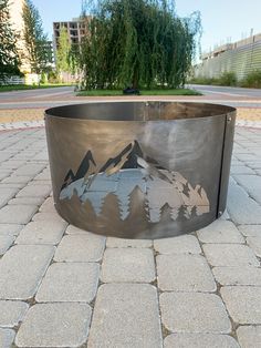 a metal fire pit sitting on top of a sidewalk