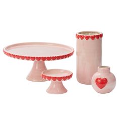 three pink vases and two plates with hearts on them