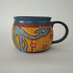 a blue and yellow ceramic cup with an image of a lizard on it's side