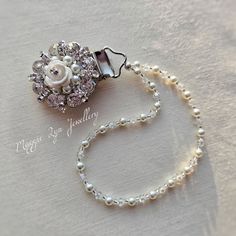 a necklace with pearls and a flower brooch sitting on top of a white cloth