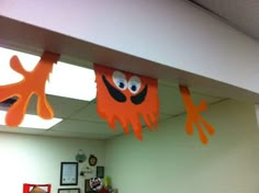 some paper cutouts are hanging from the ceiling in an office cubicle decorated with orange and black decorations