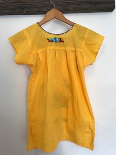 This dress can fit multiple sizes because it can be worn long or short, it's best for 5-8 years old. The measurements are provided in the pictures. It has stunning rainbow color embroidery and is a bright yellow base! It's perfect with moccasins or saltwaters in summer! It also layers well with an oversized denim jacket for colder nights by the beach! (9) Peasant Dress For Summer Festival, Summer Festival Peasant Dress, Peasant Style Summer Festival Dress, Peasant Style Beach Dress With Floral Embroidery, Folk Style Cotton Dress For Vacation, Peasant Beach Dress With Floral Embroidery, Summer Fiesta Dresses With Embroidered Neckline, Peasant Style Short Sleeve Beach Dress, Summer Short Sleeve Peasant Dress For Beach