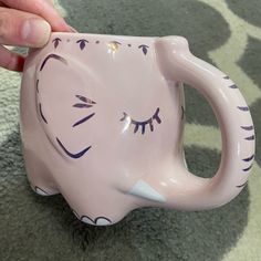 a hand holding a pink ceramic elephant mug