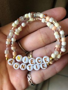 a person holding two bracelets with beads and charms that say peace on the inside