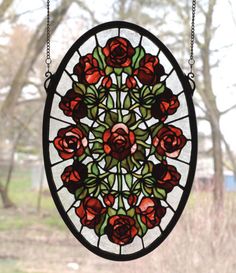 a stained glass window with red roses in the center and green leaves on it, hanging from chains