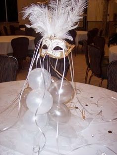 a white table topped with balloons and a masquerade mask on top of it