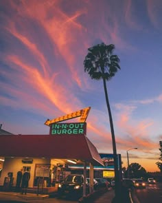 the outside of a fast food restaurant with palm trees in front of it at sunset