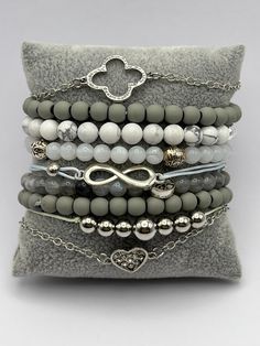 Description: Boho Chic Silver & Gray Stackable Bracelets The stacked bracelet set comes with 9 unique bracelets. These items are individually made with love by me Details: Handmade item Color: Silver & Gray  Material: Gradient Acrylic Bead, Natural Matte Hematite stone, Natural White Turquoise  Charms: Heart, Flower, Tree of Life, & Infinitive sign  Dimensions: Stretchy and Adjustable  Style: Elegant / Bohemian/ Trendy/ Retro / Indie CARE INSTRUCTIONS: Store out of direct sunlight and keep away Adjustable Gray Beaded Bracelets, Adjustable Gray Bracelet Jewelry, Adjustable Bohemian Gray Bracelet, Nickel-free Blue Bohemian Beaded Bracelets, Nickel-free Brown Bohemian Beaded Bracelets, Turquoise Charm, Trendy Bracelets, Hematite Stone, Stylish Bracelet