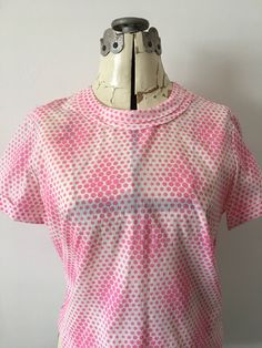 Here is a cute little blouse from the late 50's-60's. It has a rounded double collar and an all over Print of pink dots in an optical pattern. Cuffed short sleeves and a full button placket on back. Very lightweight nylon material is sheer (you can see the lines from my mannequin through the material). Tag: none. Condition: Excellent, no noted flaws. Measurements- Neck: circumference is 18 inches Shoulder to shoulder seam: 16 1/2 inches Length: 20 1/2 inches The following measurements are taken Vintage Pink Tops With Retro Print, Pink Vintage Tops With Retro Print, Retro Pink Top With Retro Print, Retro Blouse With Peter Pan Collar, Fitted Retro Pink Blouse, Pink Fitted Top With Peter Pan Collar, Fitted Short Sleeve Tops In 1950s Style, 1950s Style Fitted Short Sleeve Tops, Fitted 1950s Style Short Sleeve Tops