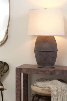 a lamp sitting on top of a wooden table next to a mirror