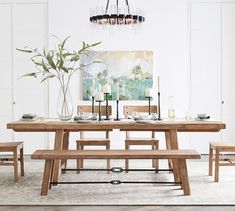 a dining room table with two benches and a painting on the wall behind it,