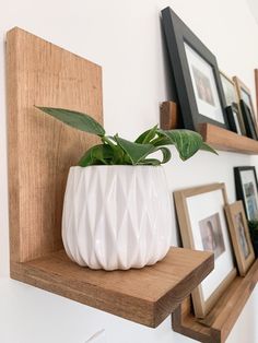 a white vase sitting on top of a wooden shelf next to pictures and framed photos