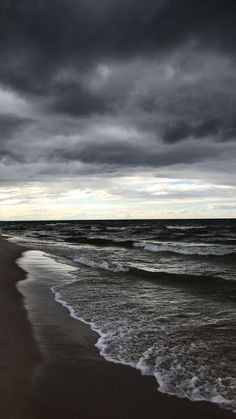 dark clouds over the ocean with waves coming in