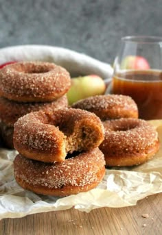 some sugared doughnuts are stacked on top of each other with an apple in the background