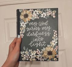 a hand holding up a book that says, my god turns my darkness into light