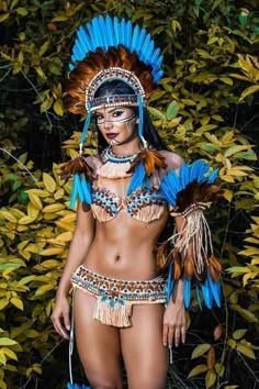 a woman in native clothing standing next to some bushes