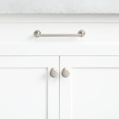 a white cabinet with two handles and knobs