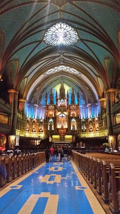 the inside of a large cathedral with stained glass windows and blue carpeted flooring