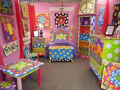 a room filled with lots of colorful furniture and decor on the walls, including a bed covered in polka dots