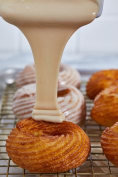 a pastry being frosted with icing on a cooling rack