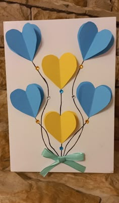 a card with blue, yellow and white balloons on it's side in the shape of hearts