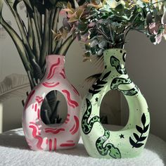 two vases with flowers in them sitting on a table next to a planter