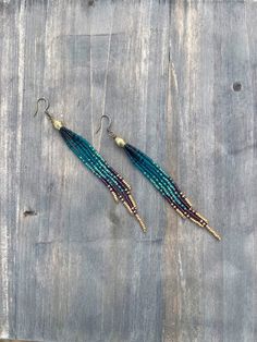 two pairs of beaded earrings sitting on top of a wooden table