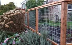 a fenced in garden area with flowers and plants growing on the side of it