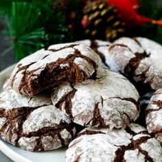 chocolate crinkle cookies on a white plate with pine cones and evergreen branches in the background