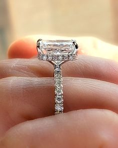 someone is holding an engagement ring in their hand, with the diamond set on it's side