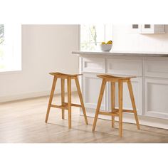 two wooden stools sitting in front of a counter