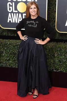 a woman standing on top of a red carpet wearing a black shirt and pleated skirt