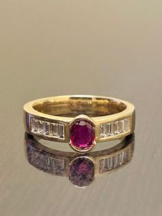 a close up of a ring with a pink stone in the middle and two baguettes on each side