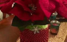 red poinsettis in a knitted vase on a table with other decorations