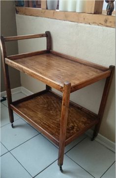 a small wooden table with two shelves on each side and a mirror in the background