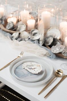 a white table topped with plates and candles