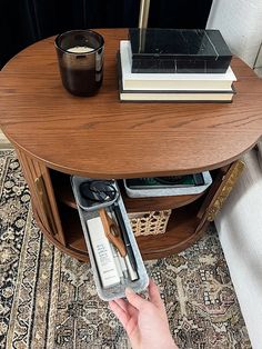 a person holding a cell phone in front of a table with books and other items on it