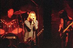 two people singing into microphones while standing in front of a stage with guitars and drums