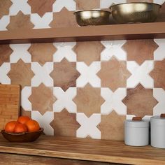 some oranges are sitting on a wooden shelf in front of a tile backsplash