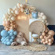 balloons are arranged around a chair and teddy bear in front of a wall with the word oh baby written on it