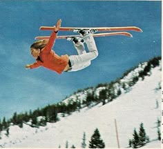 a woman flying through the air while riding skis