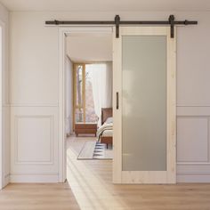 an empty room with white walls and wooden floors, sliding glass doors to the bedroom