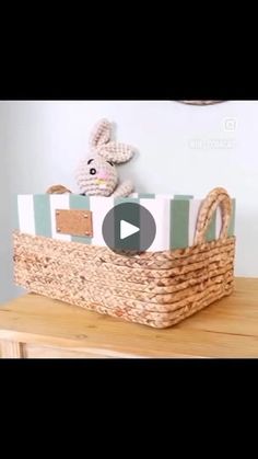 a stuffed animal sitting in a basket on top of a wooden table next to a wall