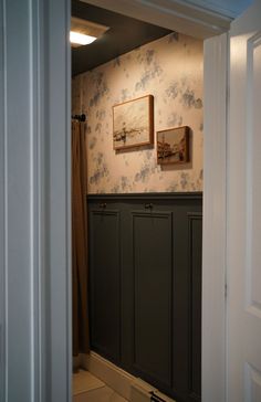 an open doorway leading to a bathroom with wallpaper and pictures on the walls above it