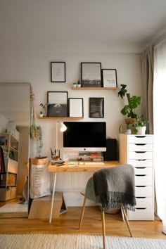 a desk with a computer on top of it in front of a window filled with pictures