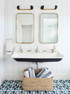 a bathroom sink with two mirrors above it and towels in a basket underneath the sink