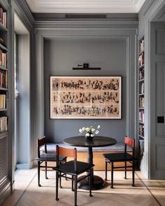 a dining room table and chairs in front of a bookshelf filled with books