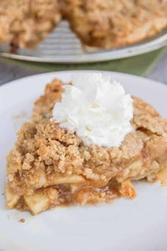 a piece of pie with whipped cream on top sitting on a white plate next to another pie