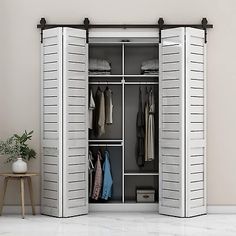 an open white closet with clothes hanging on the doors and two stools next to it